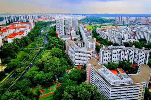 Aerial view of a cityscape with dense clusters of high-rise residential buildings interspersed with lush green trees, creating a blend of urban and nature.