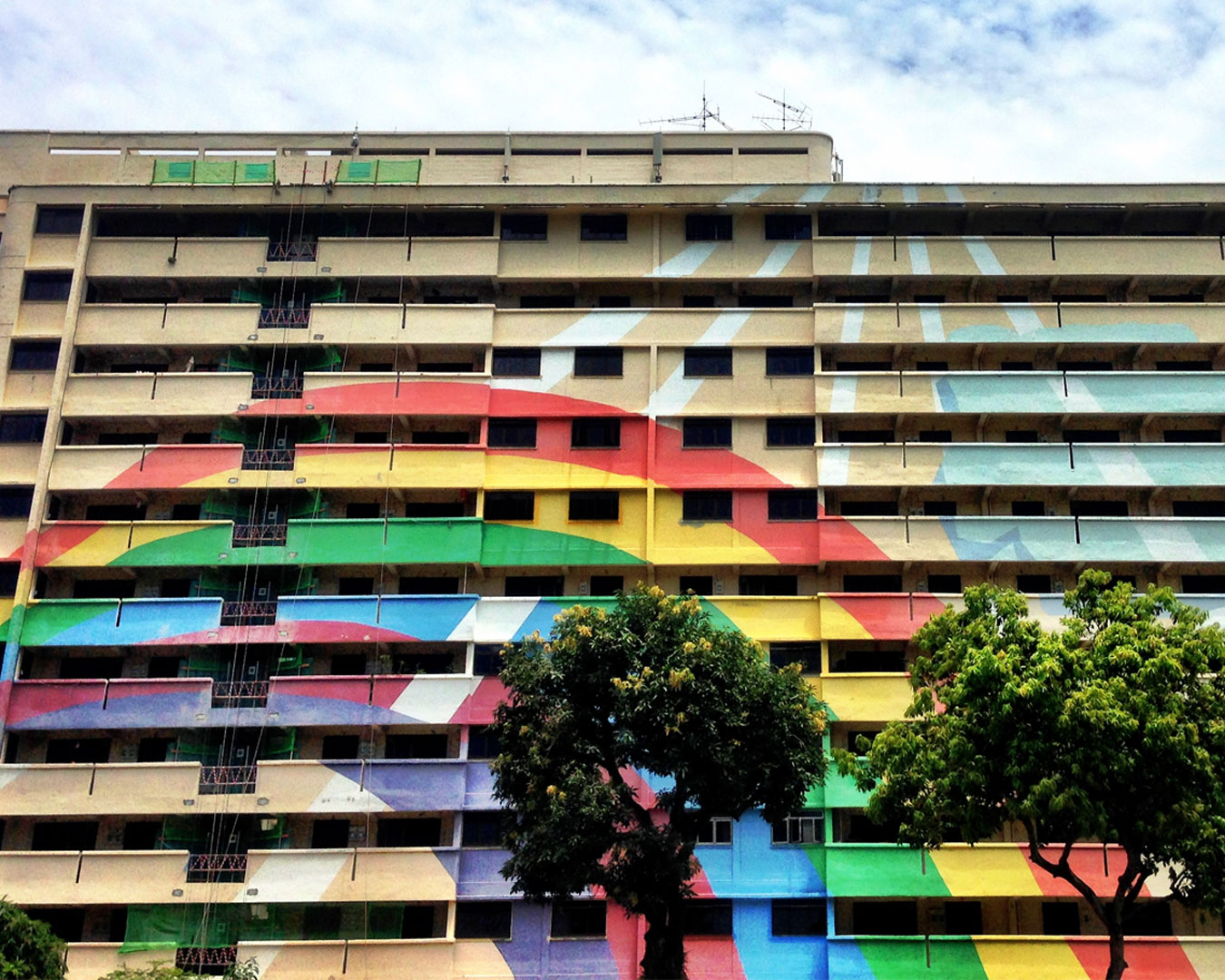 Vibrant HDB block painted in rainbow colours, standing out among surrounding buildings, a popular landmark and colourful symbol of community spirit.