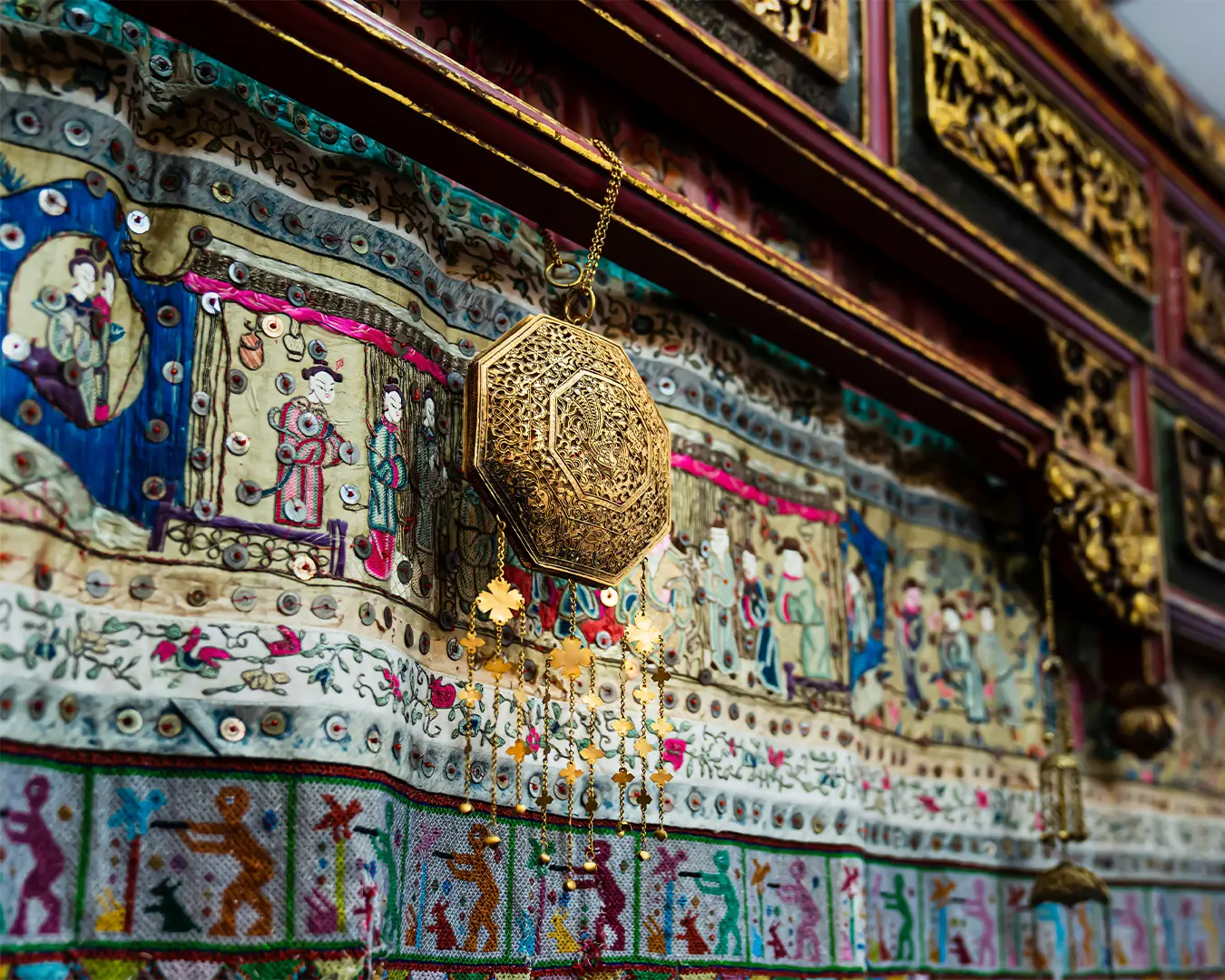 Close-up of traditional Peranakan jewellery displayed in Joo Chiat, featuring finely crafted gold pieces with delicate filigree, colourful gemstones, and detailed motifs that represent the elegance and craftsmanship of a bygone Peranakan era.