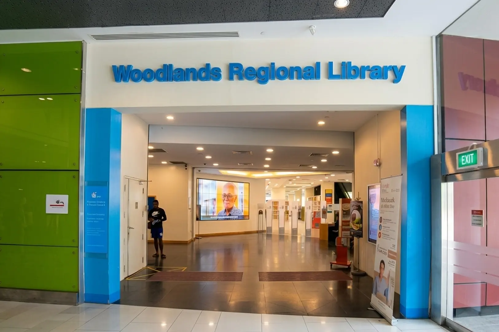 Entrance to Woodlands Regional Library with bold blue signage and colorful pillars
