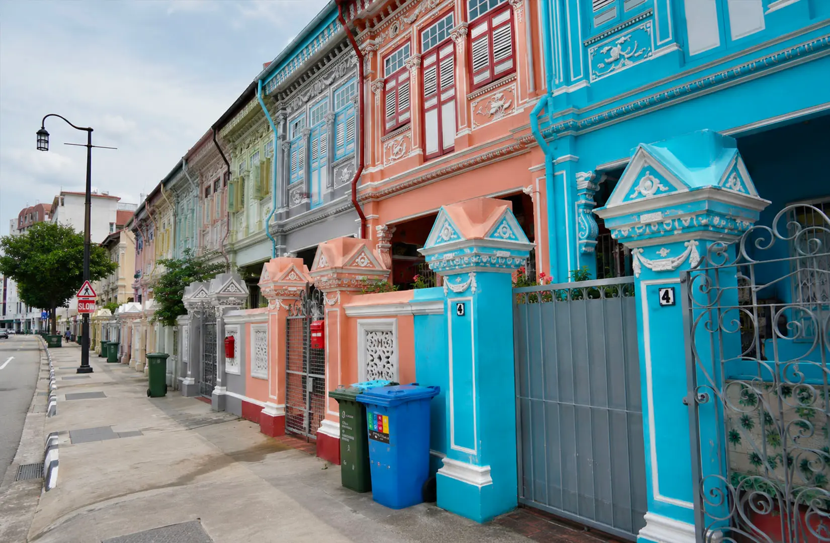 A row of charming pastel-coloured shophouses in Katong, featuring ornate Peranakan-style architecture with intricate tiles, wooden shutters, and vibrant hues that reflect the cultural heritage and nostalgic charm of the neighbourhood.