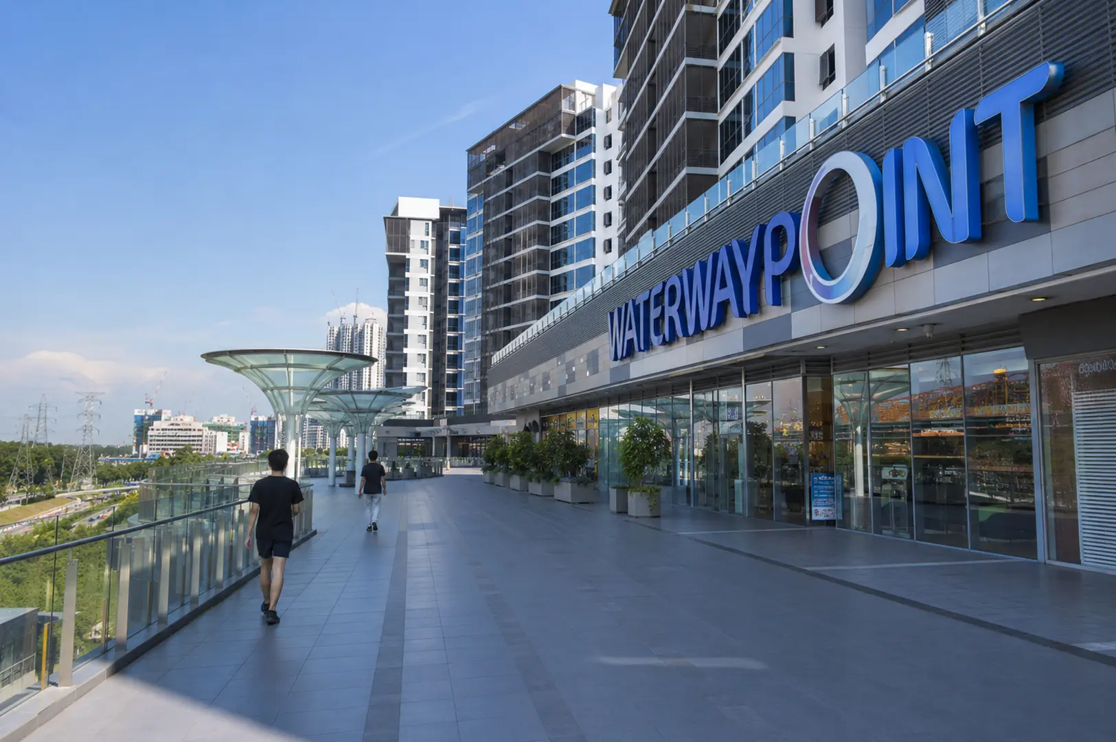 Exterior view of Waterway Point shopping mall with a pedestrian bridge and residential buildings