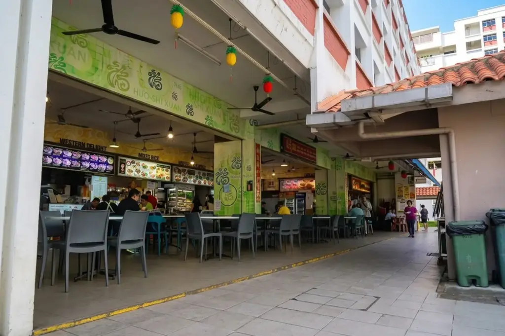 Exterior of a hawker center with green signage and dining area