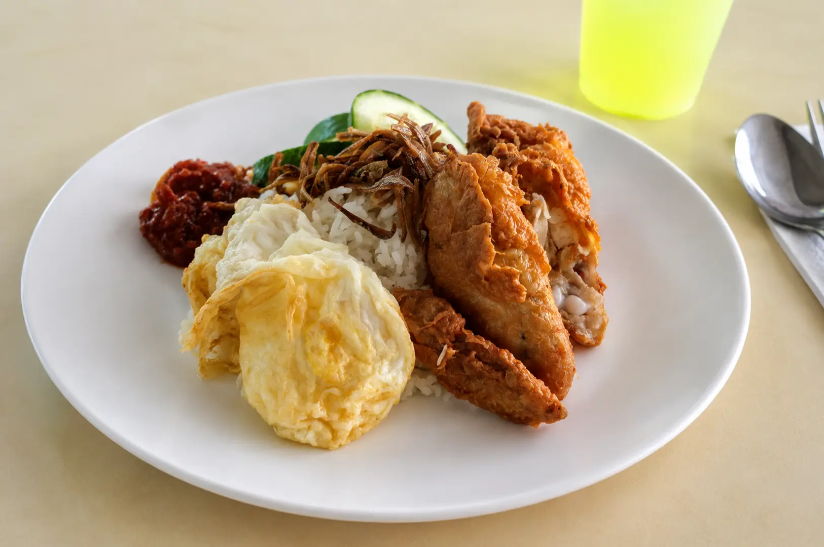 Plate of Nasi Lemak with fried chicken, egg, and sambal