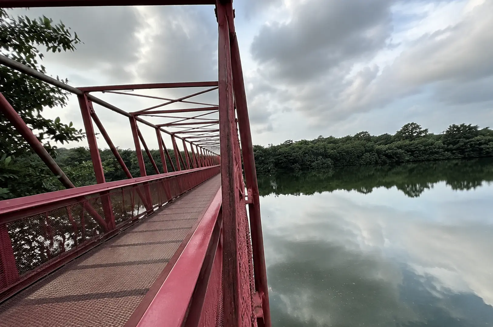 View of a red bridge at Punggol Waterway with calm water and greenery