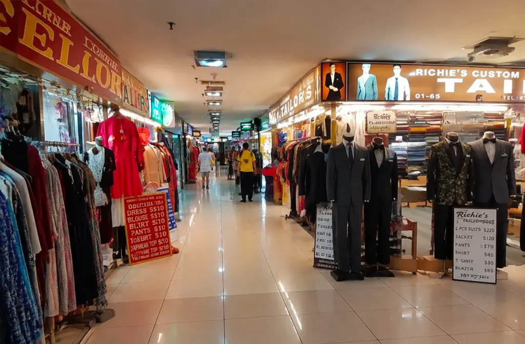 Interior corridor of Orchard Plaza filled with tailor shops and clothing displays, highlighting the building’s long-standing retail character and daily activity.