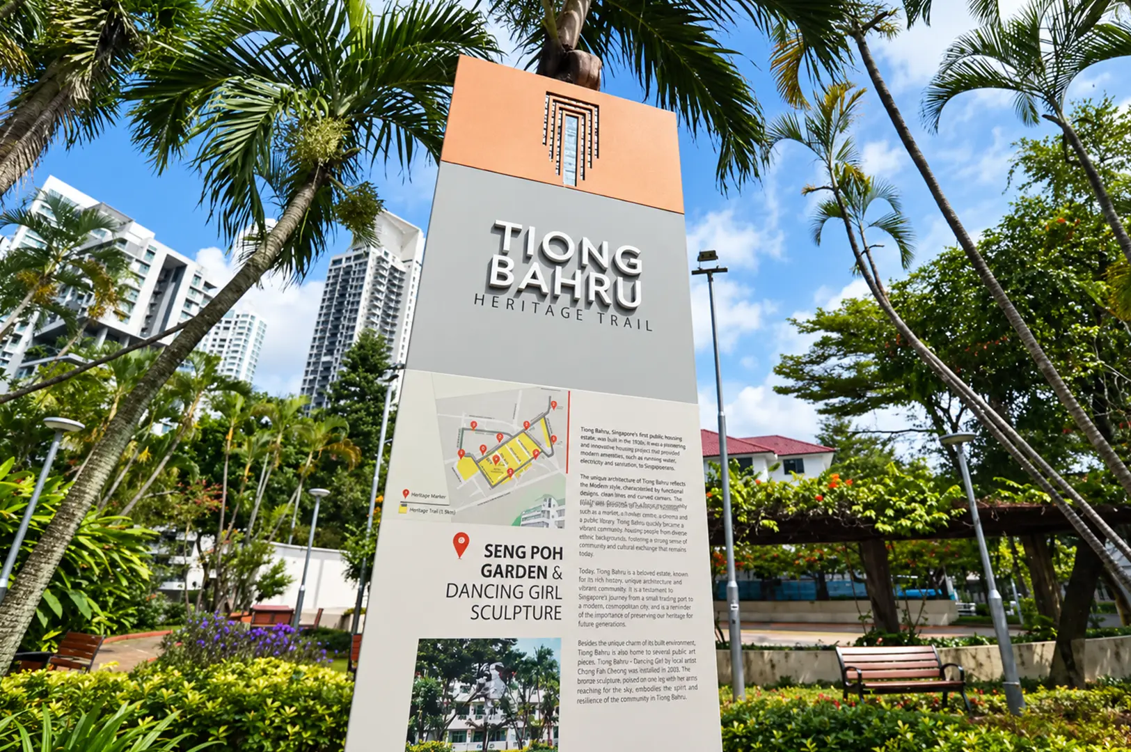 Heritage trail sign in Tiong Bahru surrounded by palm trees, lush greenery, and modern residential buildings under a bright blue sky.