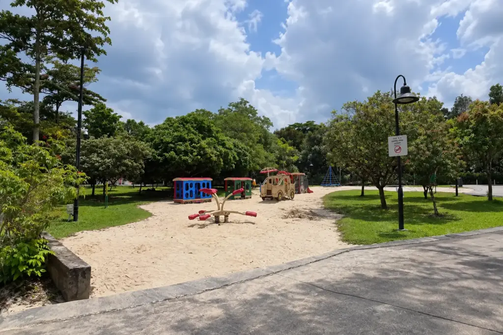 Choa Chu Kang Park with lush greenery, a sandy playground, walking paths, and bright tropical skies.
