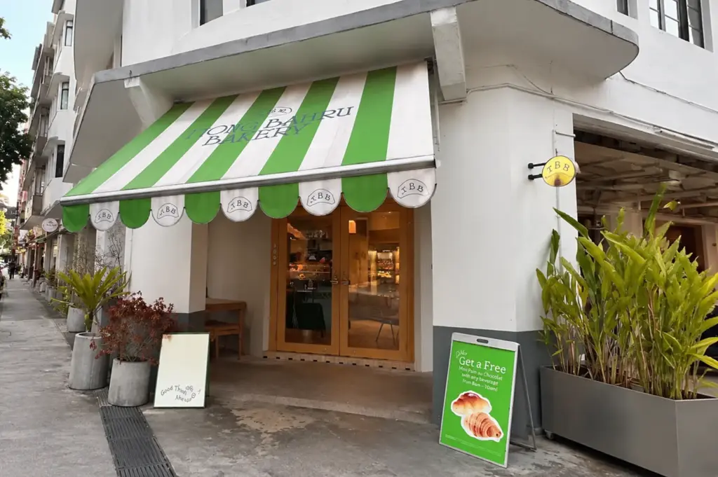 Exterior of Tiong Bahru Bakery with its signature green-and-white striped awning at the corner of a heritage shophouse.