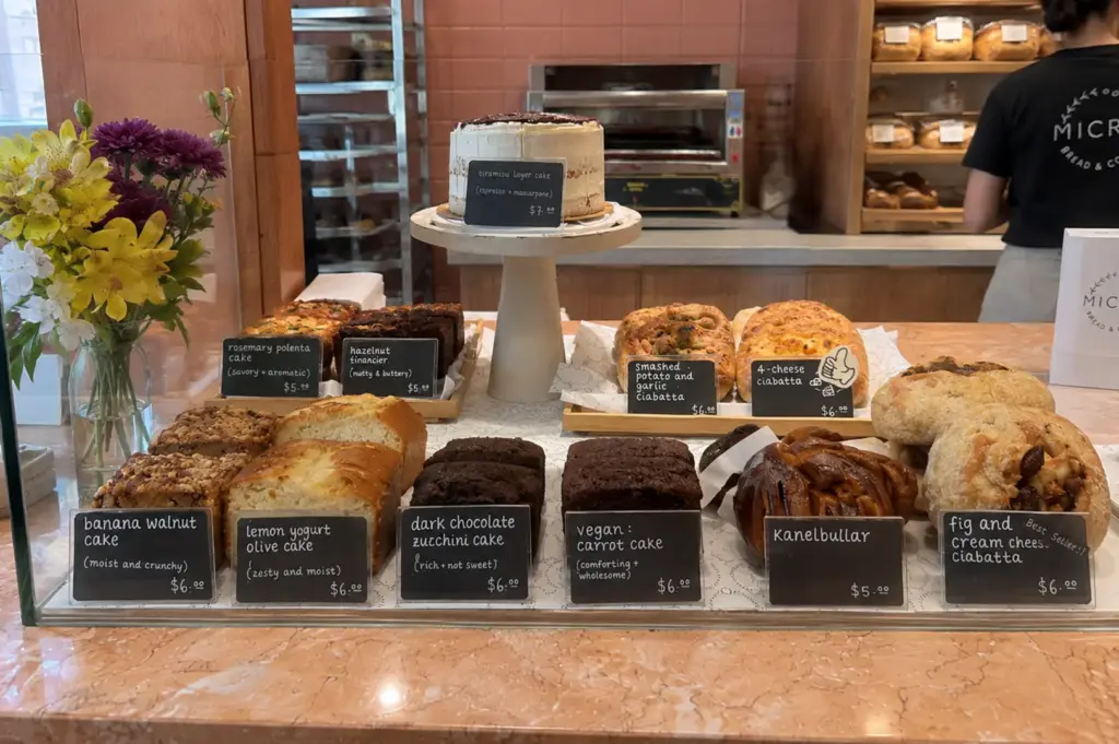 Freshly baked breads, pastries, and cakes displayed neatly on the counter inside a cozy artisan bakery.