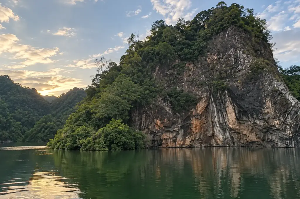 A dramatic granite cliff surrounded by lush greenery rises above a calm lake, reflecting Bukit Batok’s natural landscape and quarry heritage.