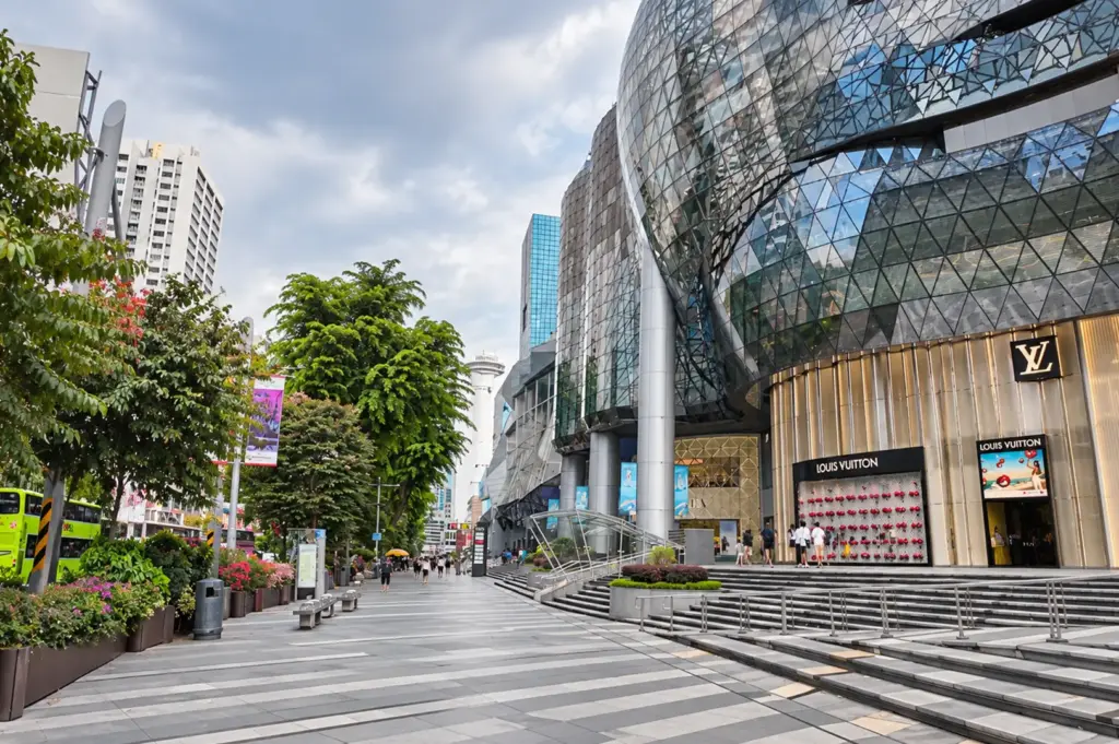 Orchard shopping district with glass-fronted ION Orchard and a tree-lined pedestrian walkway.