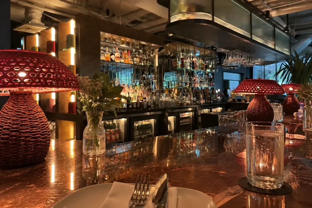 Elegant restaurant interior at Wild Honey with a marble counter, warm lighting, and decorative lamps.